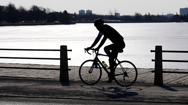 A cyclist makes their way along the edge of Dow's Lake in Ottawa on Tuesday, March 23, 2021. (Sean Kilpatrick/THE CANADIAN PRESS)
