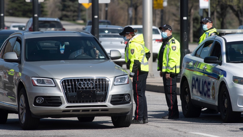 A driver shows identification to an Ottawa police officer as a checkpoint as vehicles enter the province from Quebec Monday April 19, 2021 in Ottawa. (Adrian Wyld/THE CANADIAN PRESS)