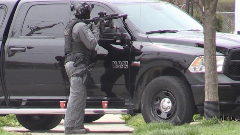 An armed officer stands in front of a property on Springbank Drive in London, Ont. on Tuesday, April 20, 2021. (Sean Irvine / CTV News)