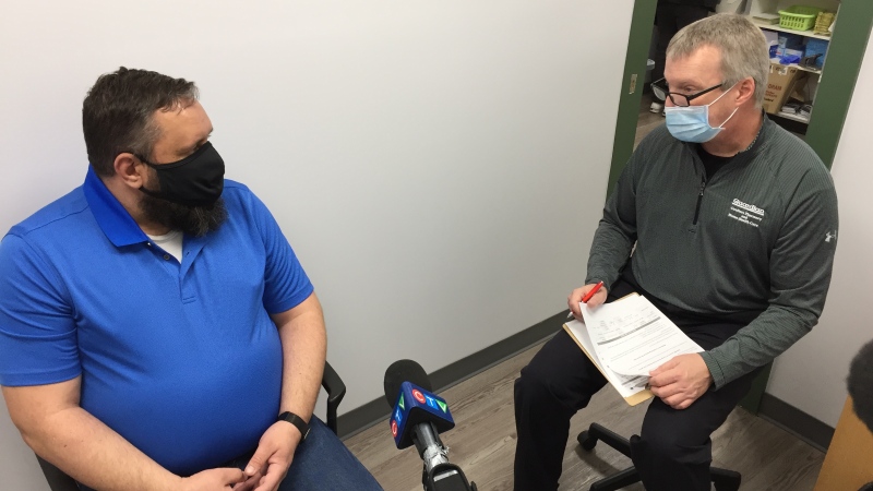 Pharmacist Scott Coulter, right, explains to client Bob Ironside what side effects to expect after receiving the AstraZeneca COVID-19 vaccine in London, Ont. on Thursday, April 22, 2021. (Bryan Bicknell / CTV News)