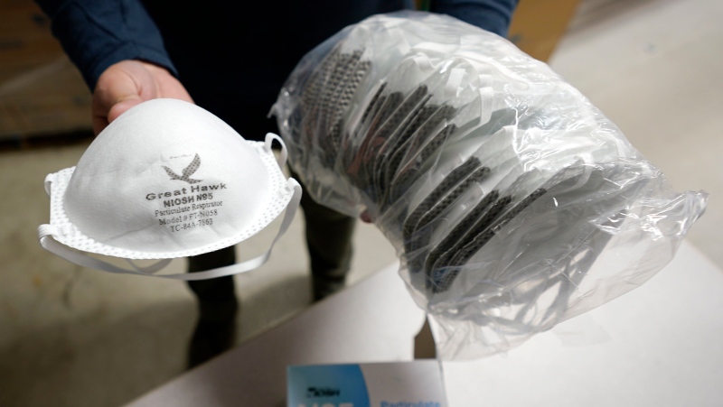 Ray Bellia holds up N95 personal protective masks, used by medical and law enforcement professionals, in the warehouse of his Body Armor Outlet store, Wednesday, Dec. 9, 2020, in Salem, N.H. (AP Photo/Charles Krupa)