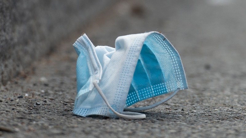 A disposable face mask is shown discarded on a street in Montreal, Sunday, April 18, 2021, as the COVID-19 pandemic continues in Canada and around the world. THE CANADIAN PRESS/Graham Hughes