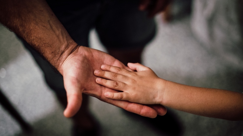Parent holding a child's hand. (Pexels, Juan Pablo)
