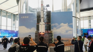 In this photo released by Xinhua News Agency, visitors view a simulated rocket launch on display at an exhibition featuring space science and achievement during the China Space Conference in Nanjing in east China's Jiangsu province on Saturday, April 24, 2021. China will launch its next robot lunar lander in 2024, and it will carry equipment from France, Sweden, Russia and Italy, the official news agency reported. (Ji Chunpeng/Xinhua via AP)