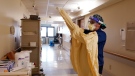 Registered Nurse Monica Quintana dons protective gear before entering a room at the William Beaumont hospital, April 21, 2021 in Royal Oak, Mich. Beaumont Health warned that its hospitals and staff had hit critical capacity levels. Michigan has become the current national hotspot for COVID-19 infections and hospitalizations at a time when more than half the U.S. adult population has been vaccinated and other states have seen the virus diminish substantially. Beaumont Health warned that its hospitals and staff had hit critical capacity levels. (AP Photo/Carlos Osorio)