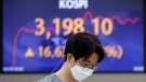 A currency trader walks near the screen showing the Korea Composite Stock Price Index (KOSPI) at the foreign exchange dealing room in Seoul, South Korea, Thursday, April 29, 2021. (AP Photo/Lee Jin-man)