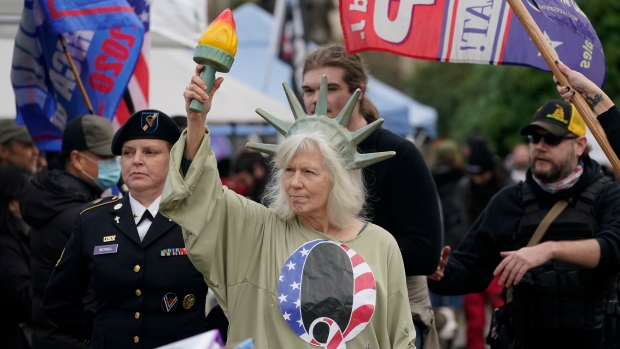 A person dressed as Lady Liberty wears a shirt with the letter Q, referring to QAnon, as protesters take part in a protest, Wednesday, Jan. 6, 2021, at the Capitol in Olympia, Wash.