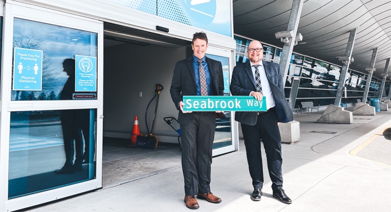 Michael Seabrook, left, who is retiring as CEO of the London International Airport, holds a new road sign with his name. (Source: London International Airport)