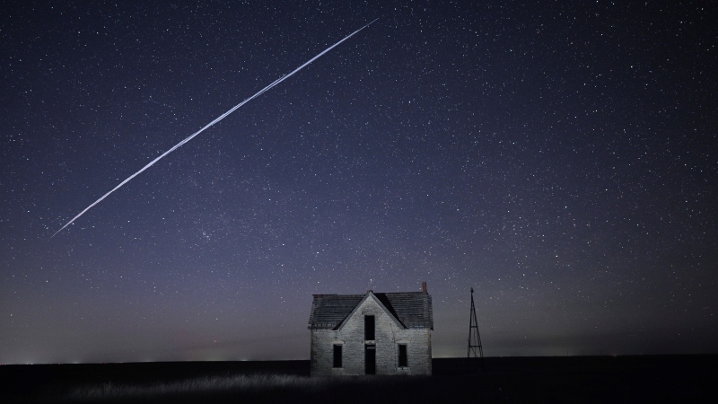 In this photo taken with a long exposure, a string of SpaceX StarLink satellites passes over an old stone house near Florence, Kan., Thursday, May 6, 2021. (AP Photo/Reed Hoffmann)