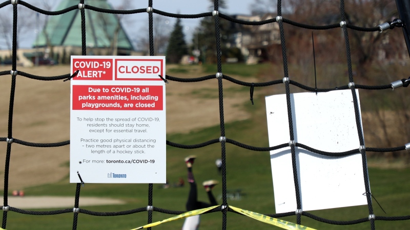 A girl tries a handstand in a Toronto park near a playground closed due to the COVID-19 pandemic on Monday, April 6, 2020. THE CANADIAN PRESS/Colin Perkel