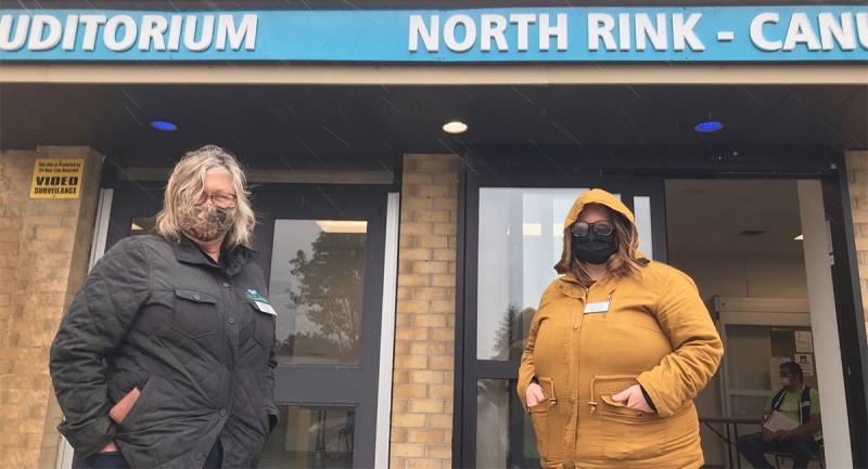 Despite a steady rain, Thames Centre Mayor Alison Warwick, left, and Deputy Mayor Kelly Elliott were greeting people out front of a mobile vaccination centre at the Dorchester, Ont. Flight Exec Community Centre, Friday, May 28, 2021. (Sean Irvine / CTV News)