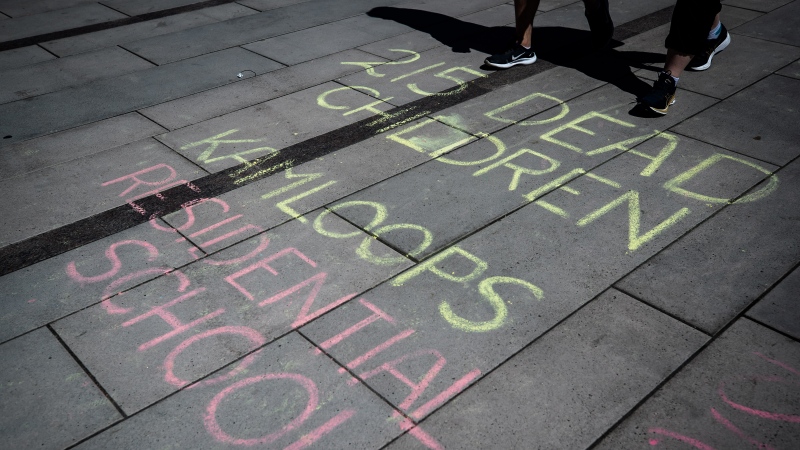 A message about the 215 children whose remains have been found buried at the site of a former residential school in Kamloops, is written in chalk on the ground in Vancouver, on Friday, May 28, 2021. (THE CANADIAN PRESS/Darryl Dyck )