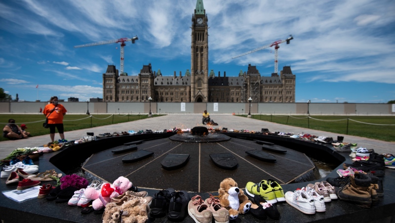 Shoes line the edge of the Centennial Flame on Parliament Hill in memory of the 215 children whose remains were found at the grounds of the former Kamloops Indian Residential School at Tk’emlups te Secwépemc First Nation in Kamloops, B.C., on Sunday, May 30, 2021, THE CANADIAN PRESS/Justin Tang 