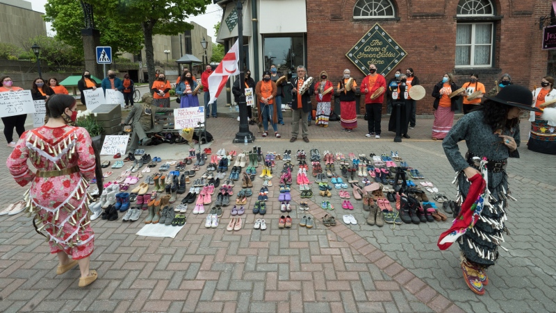 Two Indigenous dancers perform around the 215 pairs of children's shoes placed next to a Sir John A. MacDonald statue in Charlottetown on Monday, May 31, 2021 during a ceremony for the 215 children found at the Kamloops Indian Residential School.THE CANADIAN PRESS/John Morris 
