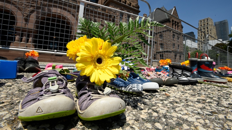 Children's shoes and flowers are shown after being placed outside the Ontario legislature in Toronto on Monday, May 31, 2021. The items were placed as a tribute after the discovery of the remains of 215 children found on the grounds of a former residential school in Kamloops last week. THE CANADIAN PRESS/Frank Gunn 