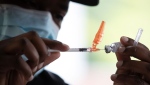 Fraser Health registered nurse Kai Kayibadi draws a dose of the Pfizer COVID-19 vaccine into a syringe at a walk-up vaccination clinic at Bear Creek Park, in Surrey, B.C., on Monday, May 17, 2021. (THE CANADIAN PRESS/Darryl Dyck)