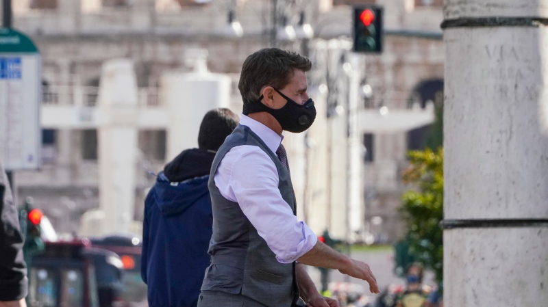 Actor Tom Cruise wears a face mask to prevent the spread of COVID-19 as he greets fans during a break from shooting Mission Impossible 7, along Rome's Fori Imperiali avenue, with the ancient Colosseum in the background, Tuesday, Oct. 13, 2020. (AP Photo/Andrew Medichini) 