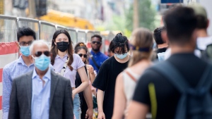 People wear face masks as they walk along a street in Montreal, Sunday, June 13, 2021, as the COVID-19 pandemic continues in Canada and around the world. THE CANADIAN PRESS/Graham Hughes 