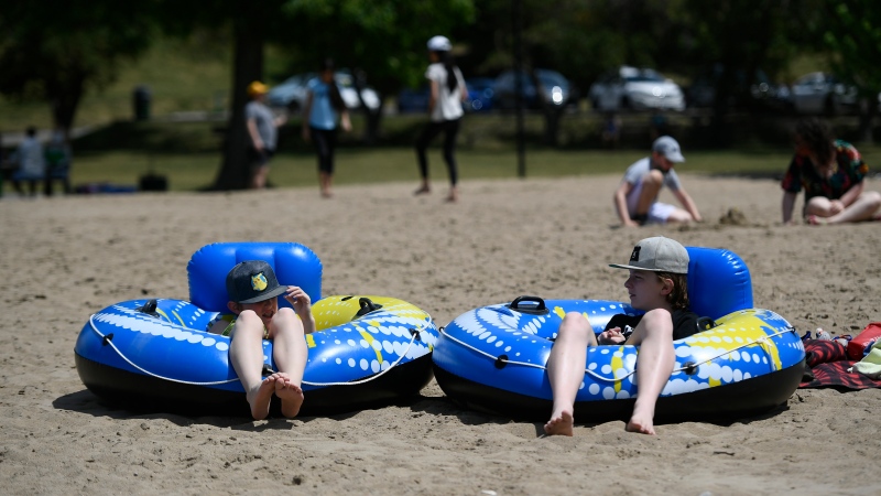 Matthew Nadon, 10, and his brother James Gordon, 13, sit in their inflatable tubes after floating in the Rideau River at Mooney's Bay Beach in Ottawa, on Saturday, June 12, 2021. (Justin Tang/THE CANADIAN PRESS)