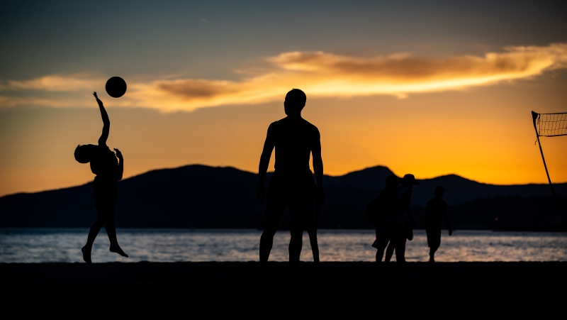 A young boy is silhouetted while playing volleyball at English Bay Beach at sunset, in Vancouver, B.C., on Monday, June 21, 2021. THE CANADIAN PRESS/Darryl Dyck 