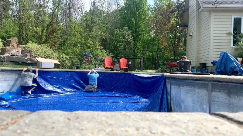 Workers install a backyard pool in this undated file image.