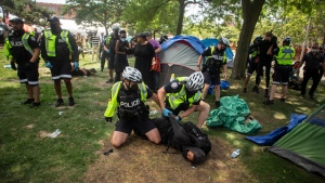 Toronto police detain encampment supporters as they clear the Lamport Stadium Park encampment in Toronto on Wednesday July 21, 2021. The operation came a day after a different encampment was cleared at a downtown park. The city has cited the risk of fires and the need to make parks accessible to everyone as factors behind the clearings. THE CANADIAN PRESS/Chris Young