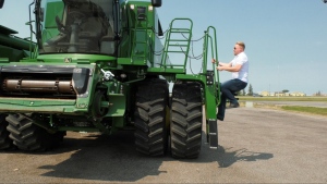 Matthew Almusa climbing into a combine at his work South Country Equipment in Emerald Park. (Kaylyn Whibbs / CTV News)