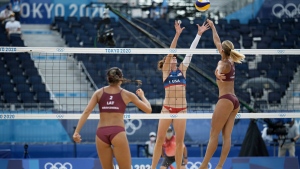 Kelly Claes, the United States and Tina Graudina, of Latvia, battle at the net as teammate Anastasija Kravcenoka looks on during a women's beach volleyball match at the 2020 Summer Olympics, July 26, 2021, in Tokyo, Japan. (AP Photo/Felipe Dana) 