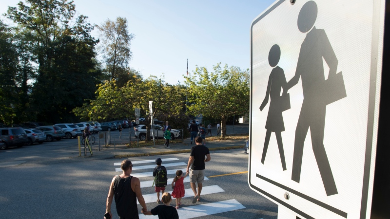 Children walk with their parents to Sherwood Park Elementary in North Vancouver for the first day back-to-school Thursday, September 10, 2020. (THE CANADIAN PRESS/Jonathan Hayward) 