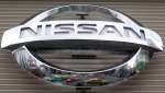 In this Feb. 8, 2012, file photo, vehicles are reflected on the logo of the Nissan Motors Co. at a showroom in Tokyo's Ginza shopping district. (AP Photo/Shizuo Kambayashi, File) 
