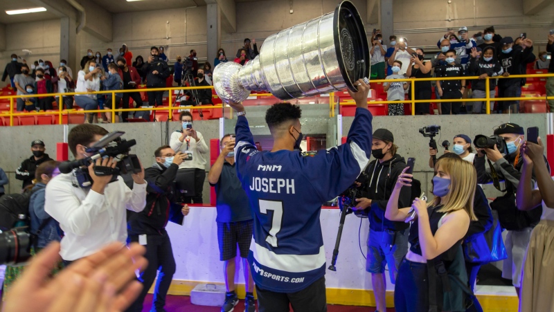 Tampa Bay Lightning Mathieu Joseph holds the Stanley cup high as he leaves the Fleury Arena in Montreal, Sunday, Aug. 15, 2021. Joseph, a Canadian on the Lightning's roster, is taking the Stanley cup for a tour in the area he grew up in and played as a youth. THE CANADIAN PRESS/Peter McCabe 