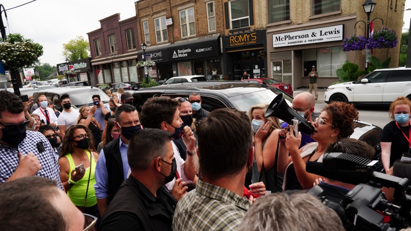 Liberal Leader Justin Trudeau is tightly boxed in as he reacts to being confronted by an anti-maskers and anti-vaxxers (holding megaphone) as he makes a whistle-stop in Aurora, Ont., on Tuesday, Aug. 17, 2021. THE CANADIAN PRESS/Sean Kilpatrick 