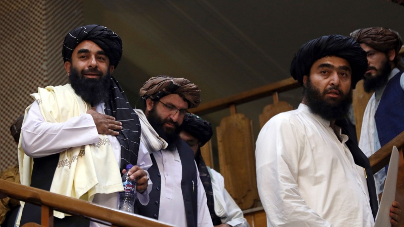 Taliban spokesman Zabihullah Mujahid, left, arrives for his first news conference at the Government Media Information Center, in Kabul, Afghanistan, Tuesday, Aug. 17, 2021. (AP Photo/Rahmat Gul)