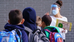 A teacher wearing protective equipment greets her students in the school yard at the Philippe-Labarre Elementary School in Montreal, on Thursday, August 27, 2020. THE CANADIAN PRESS/Paul Chiasson