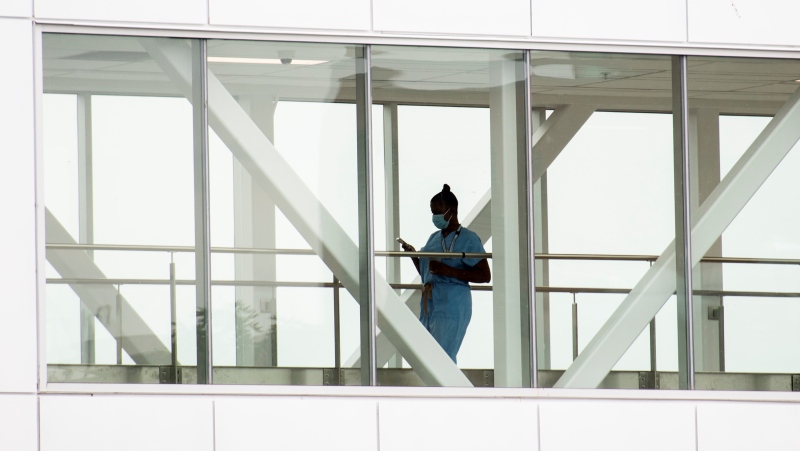 A healthcare worker crosses a covered overhead walkway at a hospital in Montreal, Tuesday, August 17, 2021, as the COVID-19 pandemic continues in Canada and around the world. THE CANADIAN PRESS/Graham Hughes 