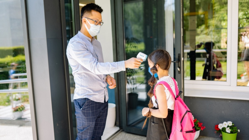 A staff member checks a student's temperature before entering the school. (Photo by Yan Krukov from Pexels)