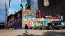 A woman walks by the colourful murals that surround the foundation for 2 World Trade Center, Sept. 8, 2021, in New York. (AP Photo/Mark Lennihan)