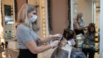A hairdresser wearing a face mask to protect against the coronavirus dyes the hair of a customer in a salon in Petralona, district of Athens, in this file photo dated Monday, Dec. 14, 2020. (AP Photo/Petros Giannakouris) 