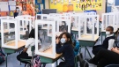 Children wearing masks sit behind screened in cubicles as they learn in their classroom after getting their pictures taken at picture day at St. Barnabas Catholic School during the COVID-19 pandemic in Scarborough, Ont., on Tuesday, October 27, 2020. THE CANADIAN PRESS/Nathan Denette 