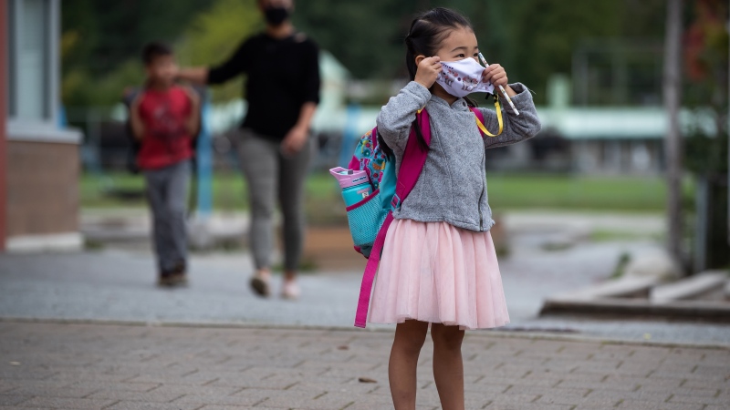 Avalynn Kwok, 4, puts on her face mask to curb the spread of COVID-19 as her parents drop her off at Lynn Valley Elementary School for her first day of kindergarten, in North Vancouver, B.C., Thursday, Sept. 9, 2021. THE CANADIAN PRESS/Darryl Dyck 