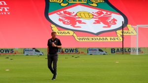 In this photo provided by Wrexham FC, Wrexham manager Phil Parkinson is seen in front of the new Kop banner the Racecourse Ground in Wrexham, Wales, Saturday, Sept. 18, 2021. (Gemma Thomas/Wrexham FC via AP) 