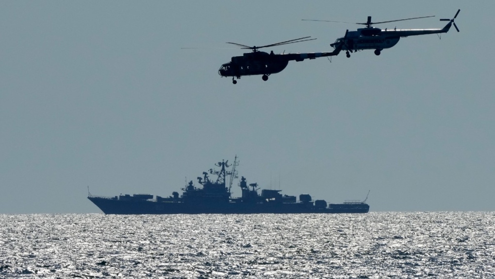 Ukrainian helicopters fly over a Russian warship