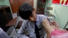 FILE- A student receives a doze of Pfizer COVID-19 vaccine from a health worker at a school in Lahore, Pakistan, Saturday, Oct. 2, 2021. (AP Photo/K.M. Chaudary)