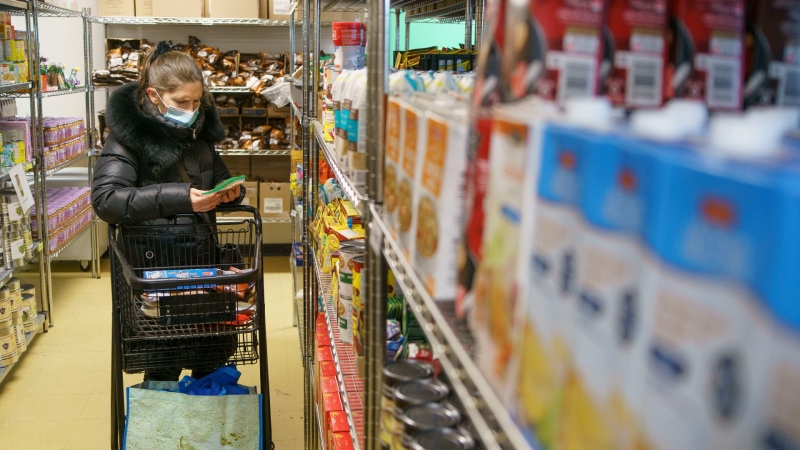 A resident of Cote-des-Neige selects food items at the MultiCaf community food bank in Montreal on Jan. 27, 2021. (THE CANADIAN PRESS/Paul Chiasson)