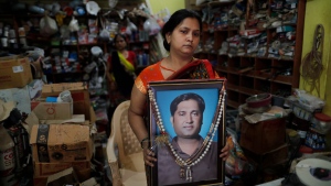 Reena Kesarwani holds a photograph of her husband, Anand Babu Kesarwani, who died of COVID-19, in their hardware shop, Monday, Oct. 25, 2021, in the Chhitpalgarh village, in India's northern Uttar Pradesh state. (AP Photo/Rajesh Kumar Singh) 