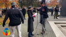 A woman at a microphone is confronted in a Kelowna, B.C. park on Remembrance Day 2021. (KelownaNow)