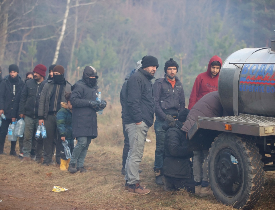 Migrants line up to collect drinking water