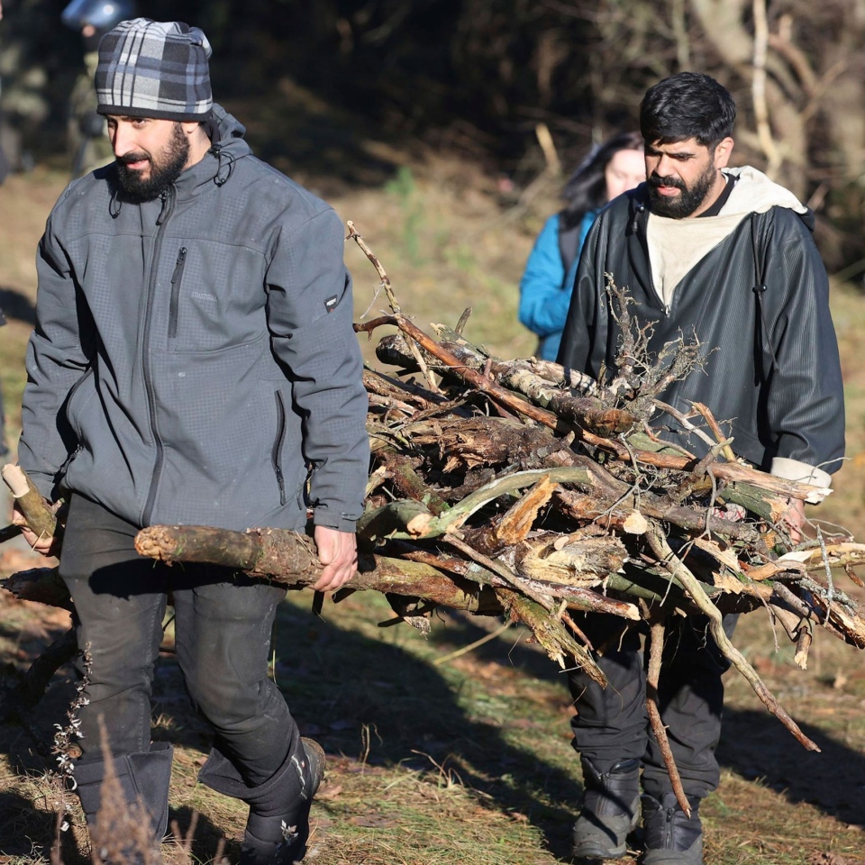 Migrants carry firewood at Poland-Belarus border