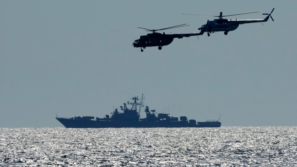 Ukrainian helicopters fly over a Russian warship
