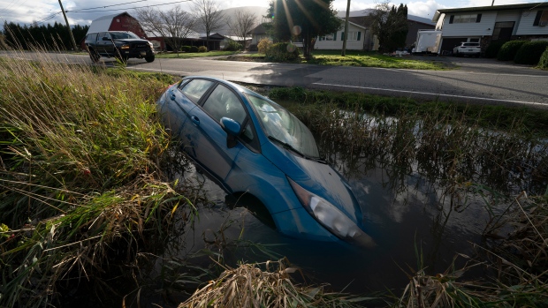 A car is seen in a flooded ditch along a road in Chilliwack, B.C., Tuesday, November 16, 2021. THE CANADIAN PRESS/Jonathan Hayward